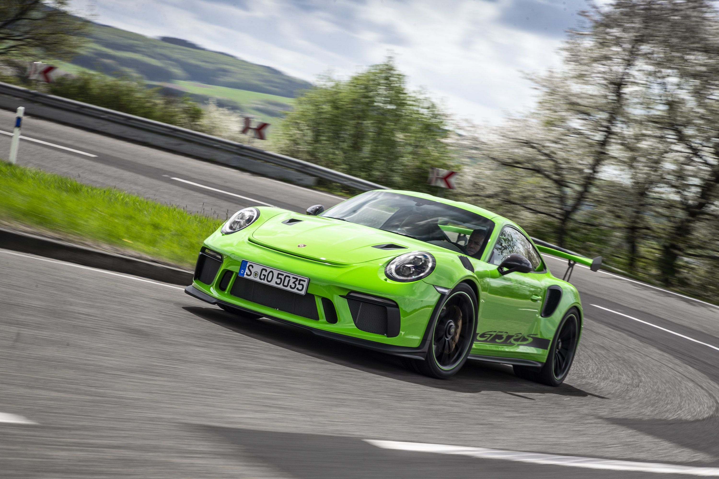Front view of a green Porsche 911 GT3RS driving on a road